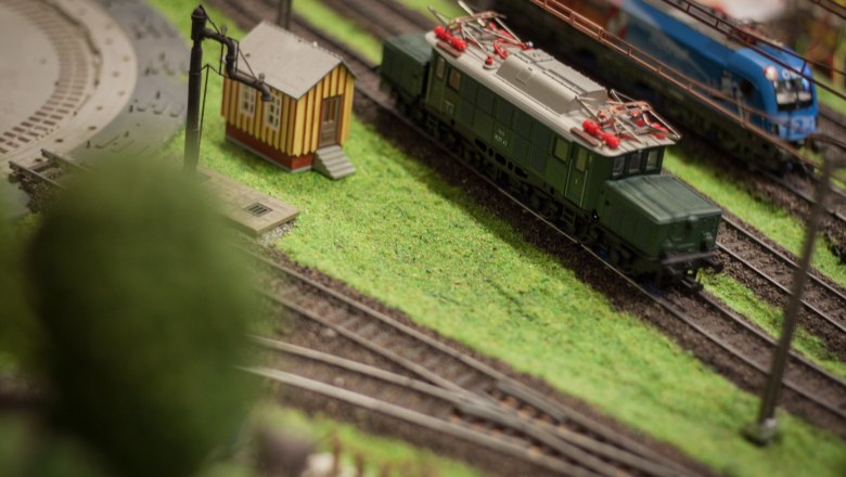 The fascination of model making, © Rene Jagersberger Model railroad with green train and small building on a layout.